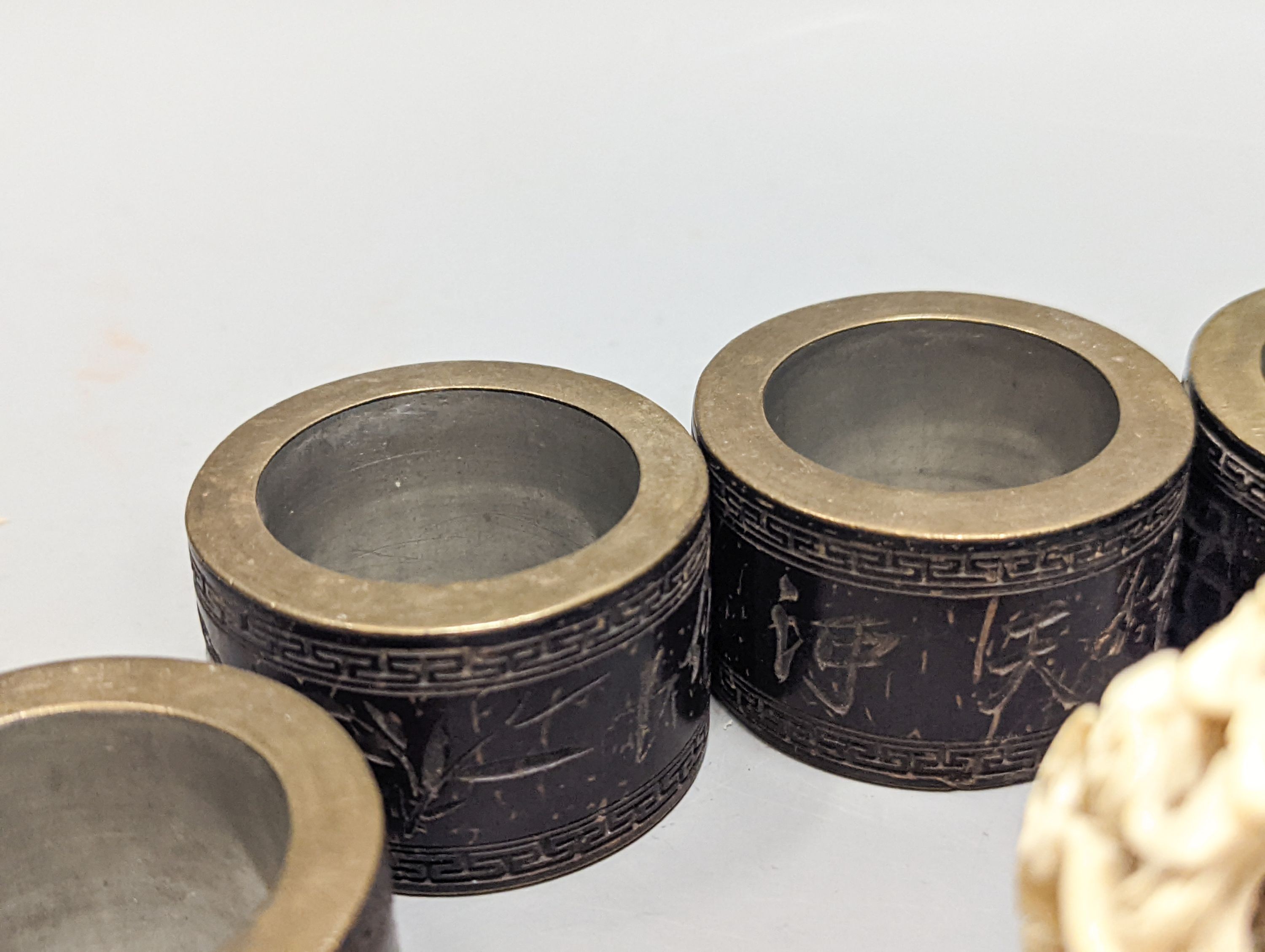 A Chinese ivory concentric puzzle ball, 6 Chinese coconut and brass mounted napkin rings.